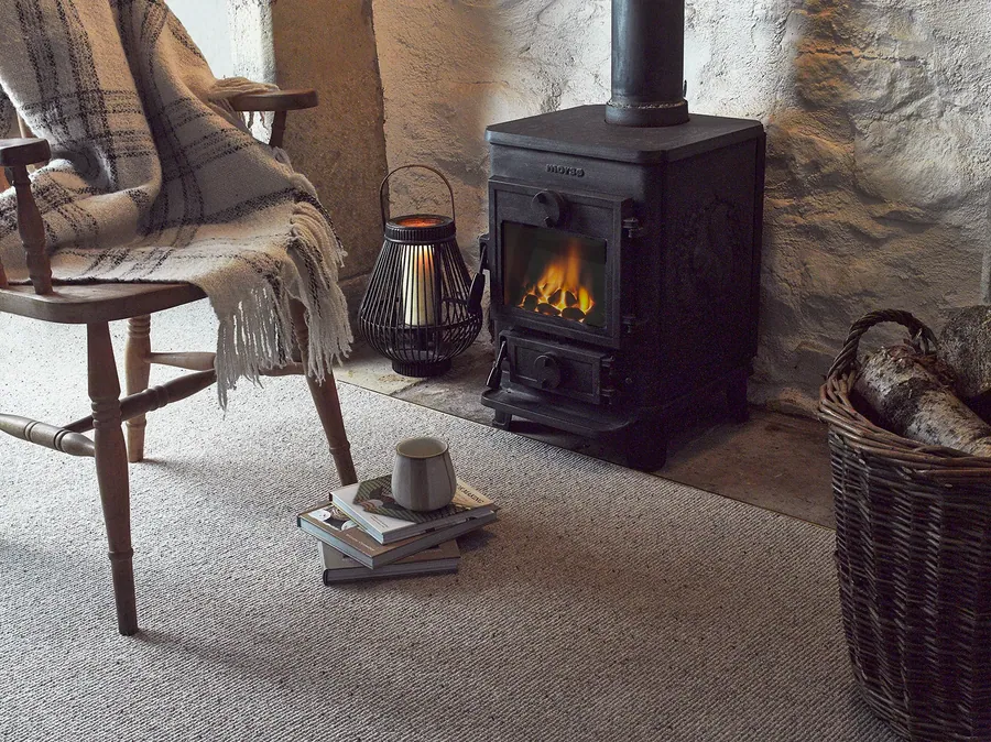Ulster Habitus Croft Soya carpet beside a wood-burning stove